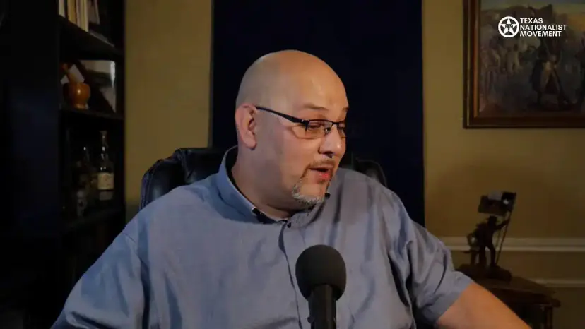 Daniel Miller turns to his side while speaking into a microphone during a livestream.