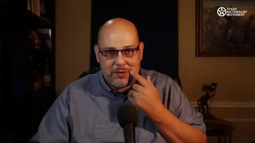 Daniel Miller rests a hand on his chin while speaking into a microphone in his home office.