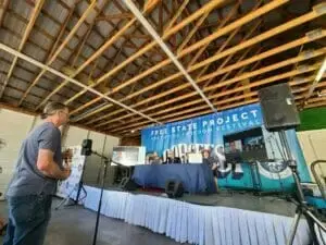 An attendee asks a question at a microphone in a pavilion with a Free State Project banner over the stage