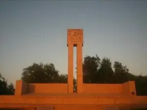 The Fannin Memorial monument at Goliad, a tall stone marker glowing orange at sunset.