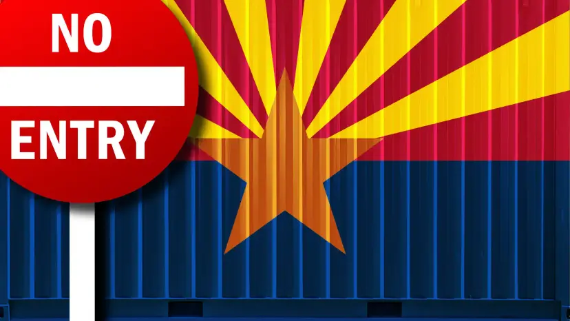Red 'No Entry' sign in front of shipping containers painted with the Arizona flag.