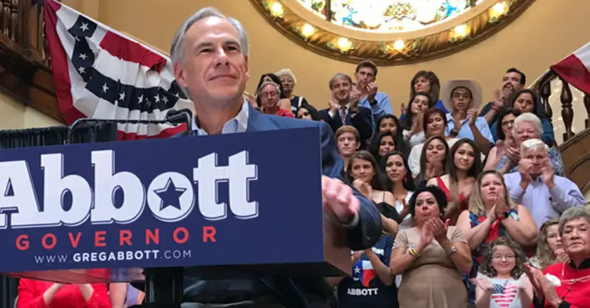 Greg Abbott at an 'Abbott Governor' podium with a cheering crowd of supporters behind him.