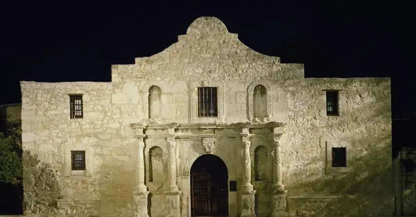 The front of the Alamo church lit up at night.