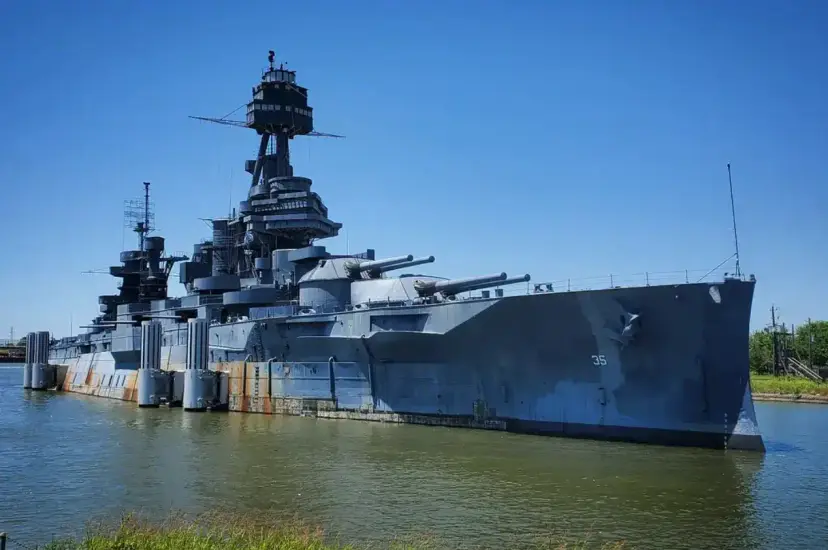 The Battleship Texas moored at the water's edge under a bright blue sky
