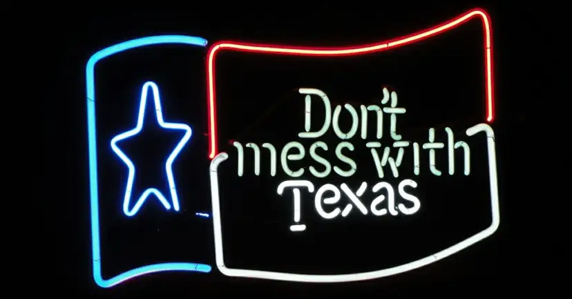 Neon sign reading 'Don't mess with Texas' beside a neon outline of the Texas flag star.