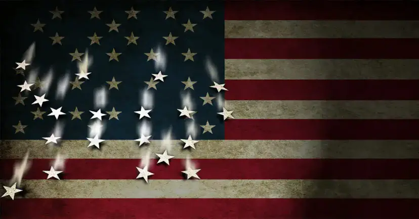 A weathered American flag with its white stars falling away from the blue field.