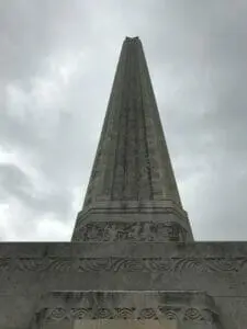The tall stone shaft of the San Jacinto Monument rising against a gray, cloudy sky.