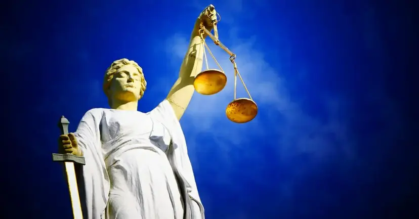 Statue of Lady Justice holding scales and a sword against a blue sky.