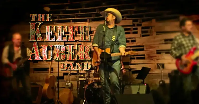 The Keefe Auber Band performing on a wooden stage, with the band name in ornate red and gold lettering.