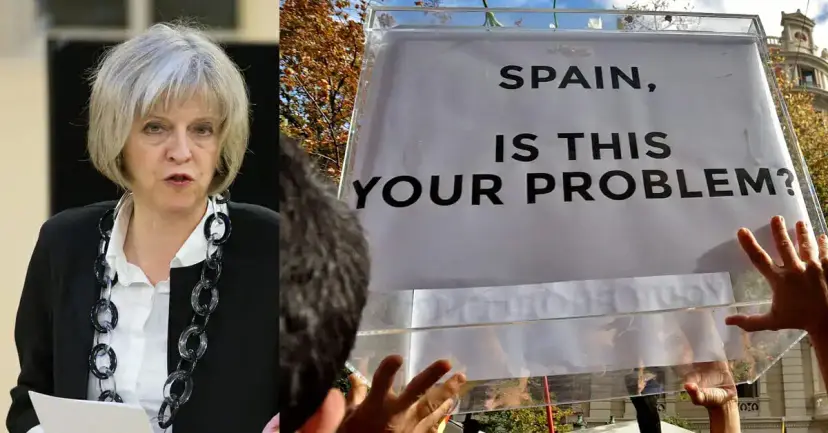 British Prime Minister Theresa May beside a protest sign reading "Spain, is this your problem?"
