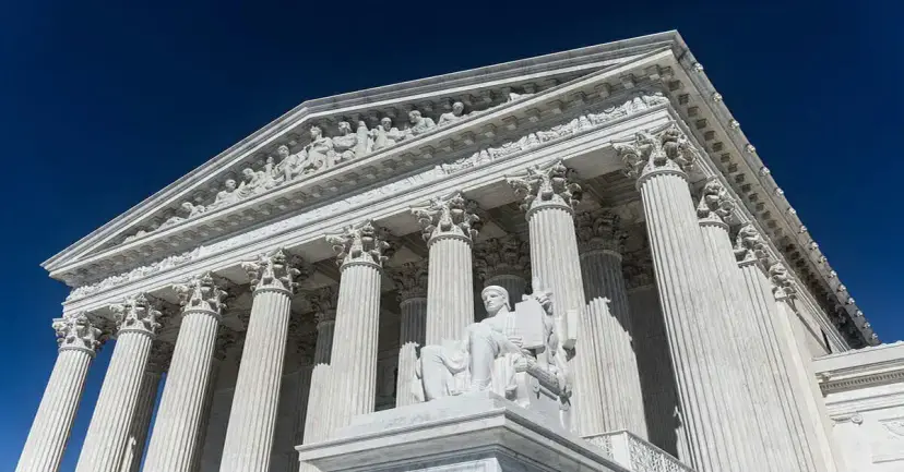 The columned marble front of the Supreme Court building in Washington against a deep blue sky.