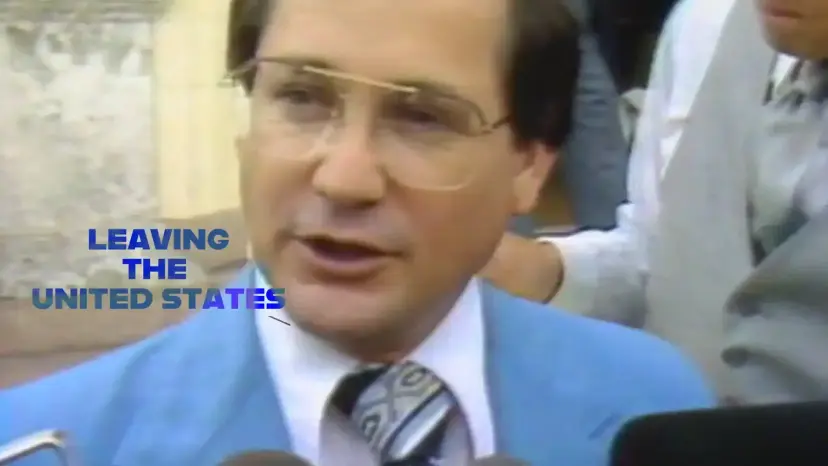 A man in a blue suit speaks to reporters, with on screen text reading 'Leaving the United States.'