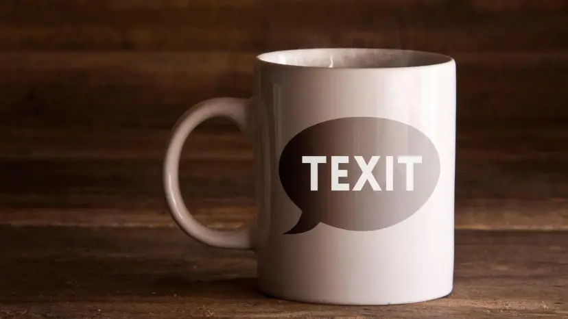 White coffee mug with a speech bubble reading 'TEXIT' on a dark wooden table
