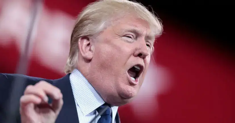 Donald Trump speaking forcefully with his mouth open and hand raised against a red background.