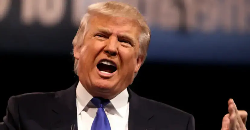 Donald Trump shouting with his mouth open and one hand raised.