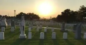Rows of white headstones and monuments in a military cemetery at sunset.