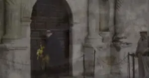 A person places a wreath at the doorway of the Alamo church