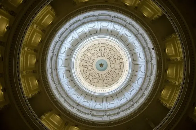 View looking straight up into the Texas Capitol rotunda dome, with a star at its center.