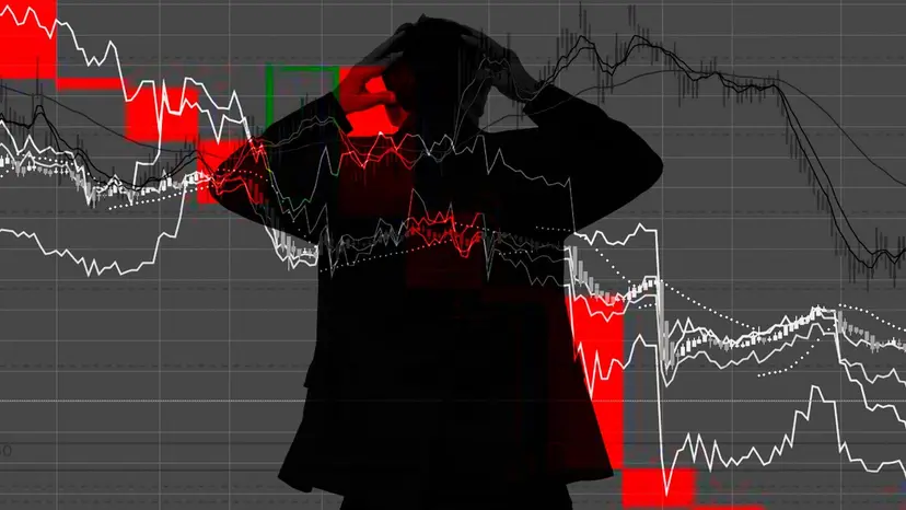 Silhouette of a person clutching their head against a falling red and white stock market chart.