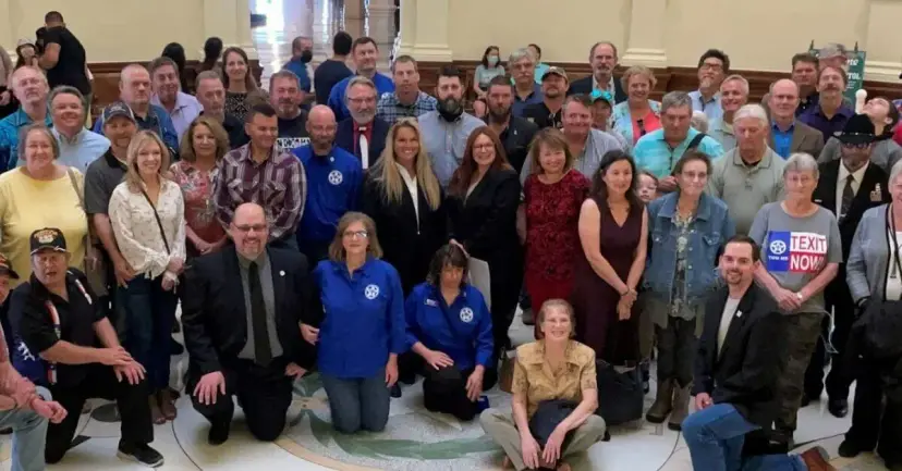 A large group of TEXIT supporters poses together inside the Texas Capitol, some holding 'TEXIT Now' signs.