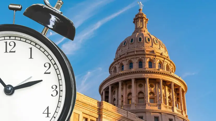 An alarm clock in the foreground beside the dome of the Texas State Capitol against a blue sky.