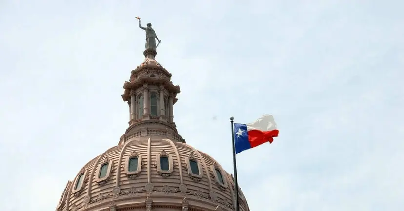 The Texas Capitol dome with the Goddess of Liberty statue and a Texas flag flying beside it.