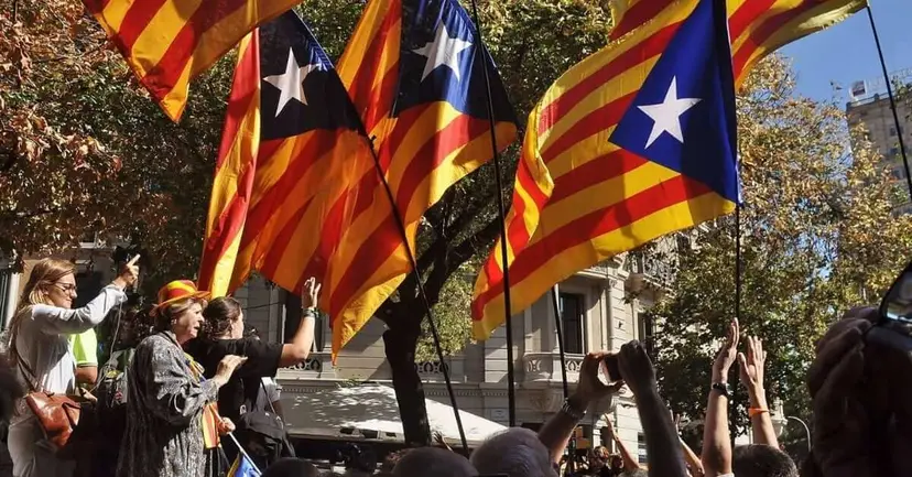 Catalan independence flags with red and yellow stripes and a white star waving above a crowd taking photos.