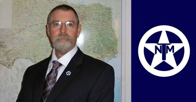 A bearded man in glasses and a suit before a Texas map, beside the white TNM star logo on navy.