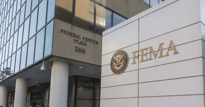 A FEMA sign at the entrance to Federal Center Plaza 500 beside a glass office building.