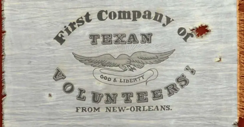 Faded historic flag reading "First Company of Texan Volunteers from New-Orleans" with an eagle and "God & Liberty."