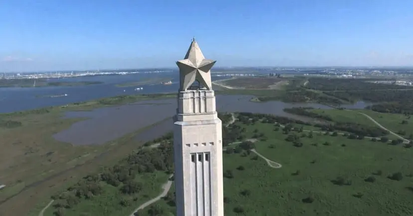 Aerial view of the star-topped San Jacinto Monument rising above green marshland and water.