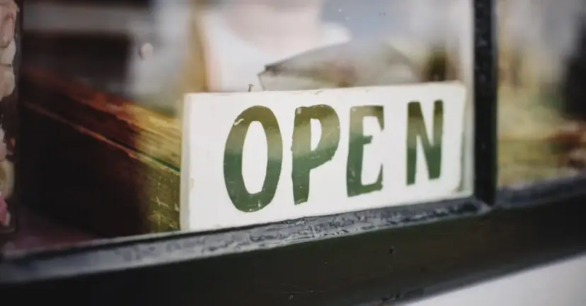 An 'Open' sign hanging in a shop window.