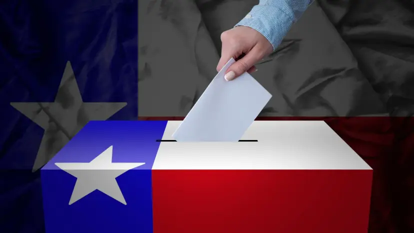 A hand dropping a ballot into a box painted like the Texas flag, with a larger Texas flag behind it.