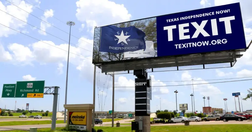Roadside billboard reading 'Texas Independence Now! TEXIT, texitnow.org' beside a blue Independence flag near a highway.