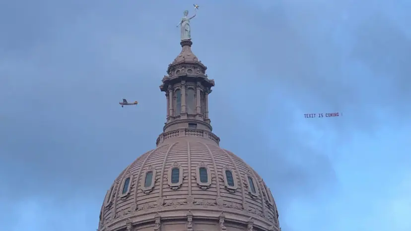 Small plane towing a banner reading 'TEXIT is coming' past the Texas Capitol dome