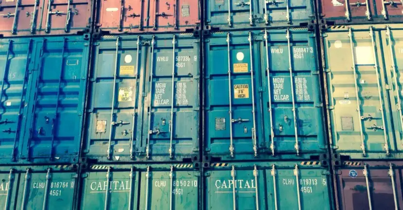 Rows of stacked shipping containers in teal, red, and green.