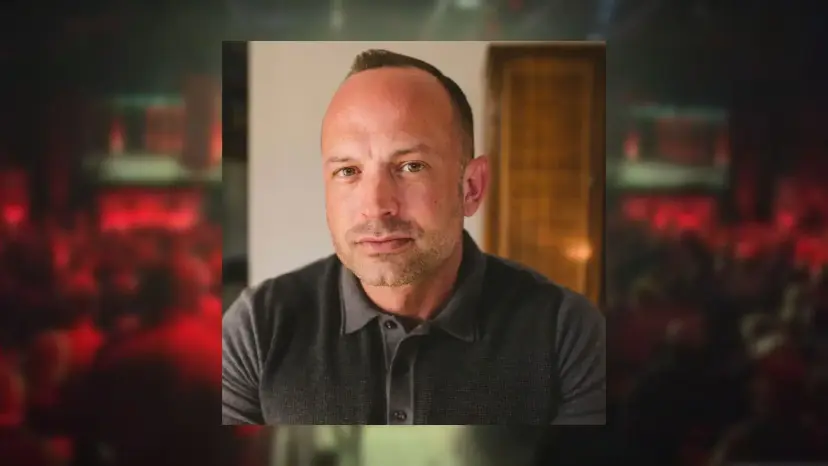 Headshot of Buck Johnson in a gray polo shirt, set over a blurred red concert hall background.
