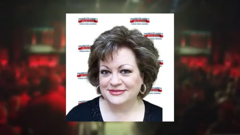 Headshot of JoAnn Fleming, a woman with short brown hair, over a blurred red hall background.