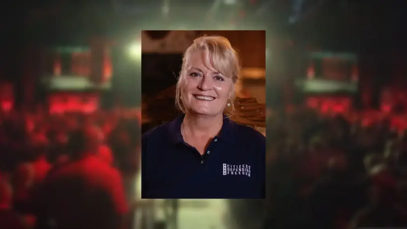 Photo of Marcia Watson, a smiling blonde woman in a navy shirt, over a blurred red hall background.