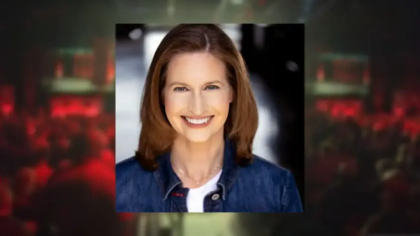 Headshot of Margaret Byfield, a smiling woman in a denim jacket, over a blurred red hall background.