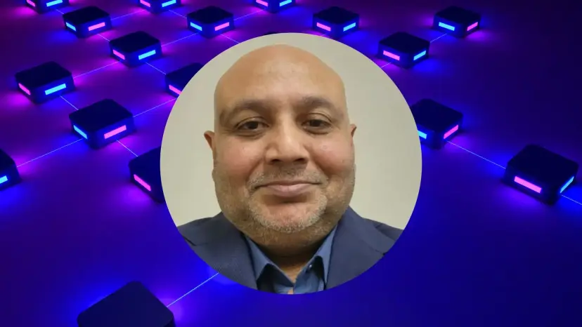 Augustin Gohil, a smiling bald man in a blue shirt and jacket, over glowing blue and purple tech blocks.