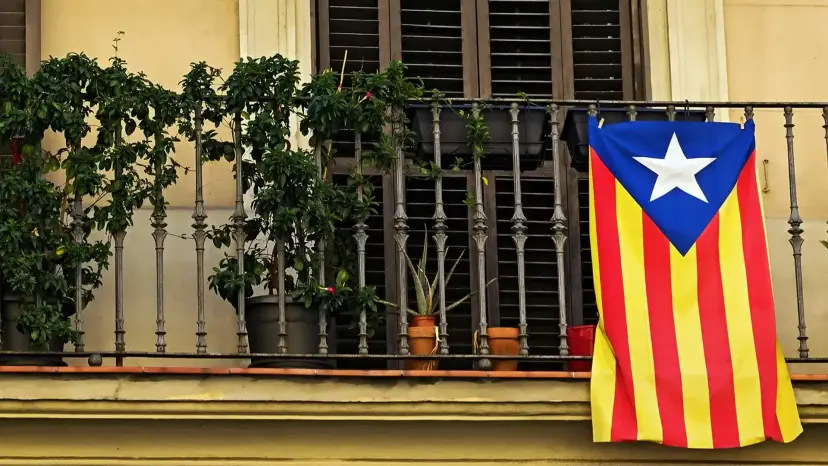 A Catalan independence flag, the Estelada, hangs from an iron balcony railing lined with potted plants.