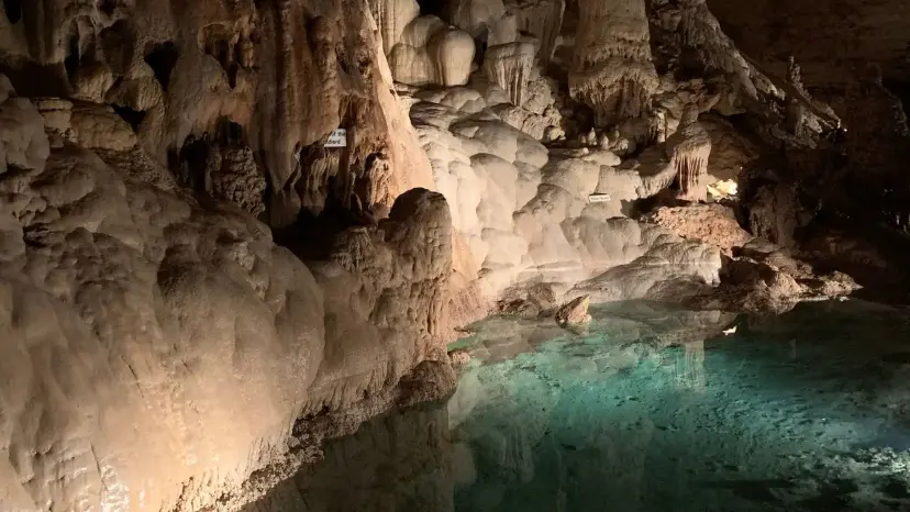 Pale limestone formations and a still green pool inside Natural Bridge Caverns.