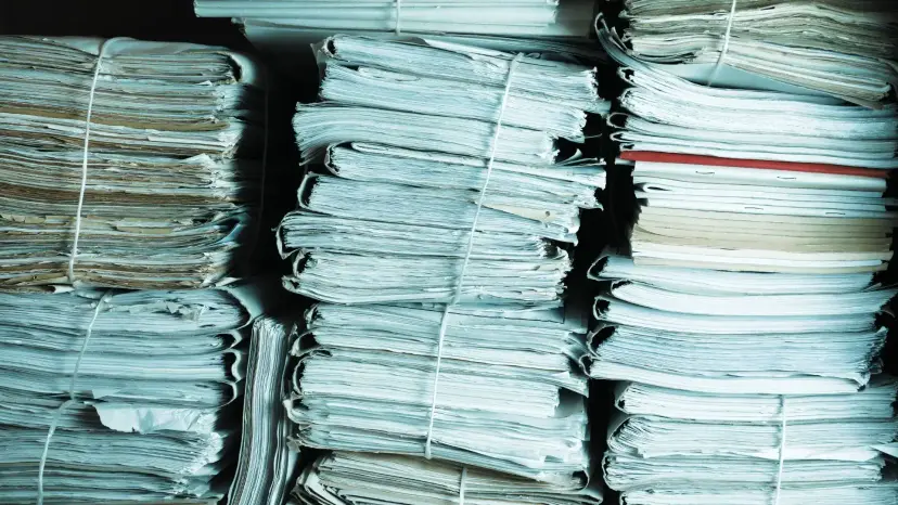 Tall stacks of bundled paper documents tied with string.