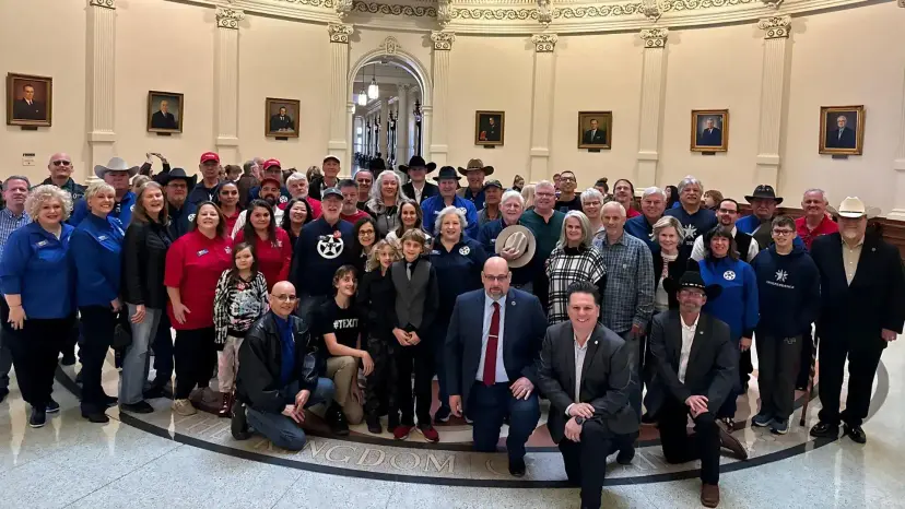 A large group of Texas Nationalist Movement supporters posing together in the Texas Capitol rotunda.