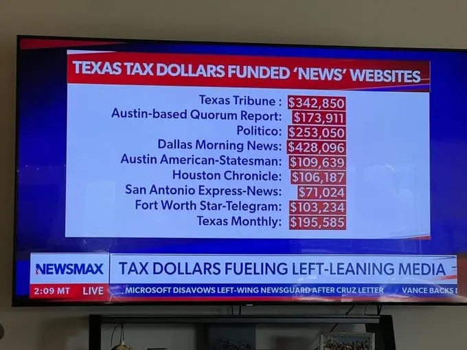 Television showing a Newsmax graphic, 'Texas Tax Dollars Funded News Websites,' listing payments to the Texas Tribune and other outlets.