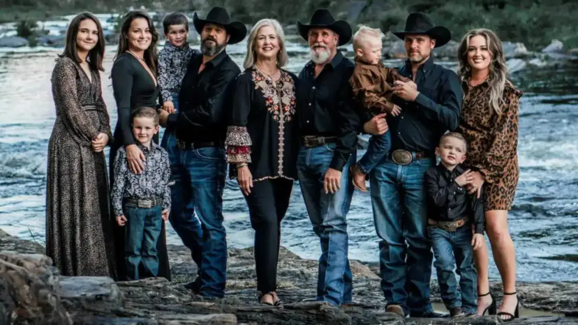 Rhonda Ward and her extended family in western wear and cowboy hats posing on rocks beside a river.