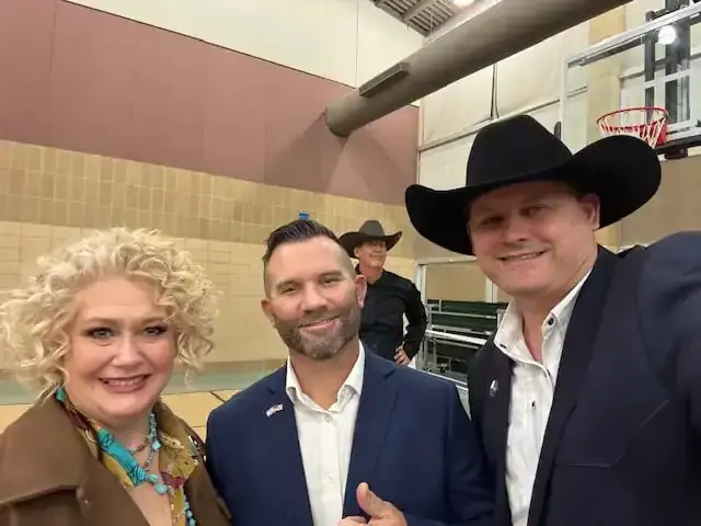 Selfie of a woman, a man in a navy suit giving a thumbs up, and a cowboy.