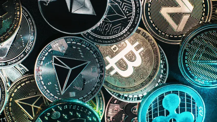 A pile of silver and gold cryptocurrency coins, including Bitcoin, Tron and Ripple designs.
