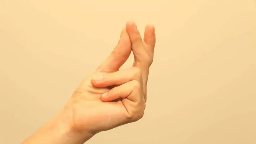A hand snapping its fingers against a plain beige background.